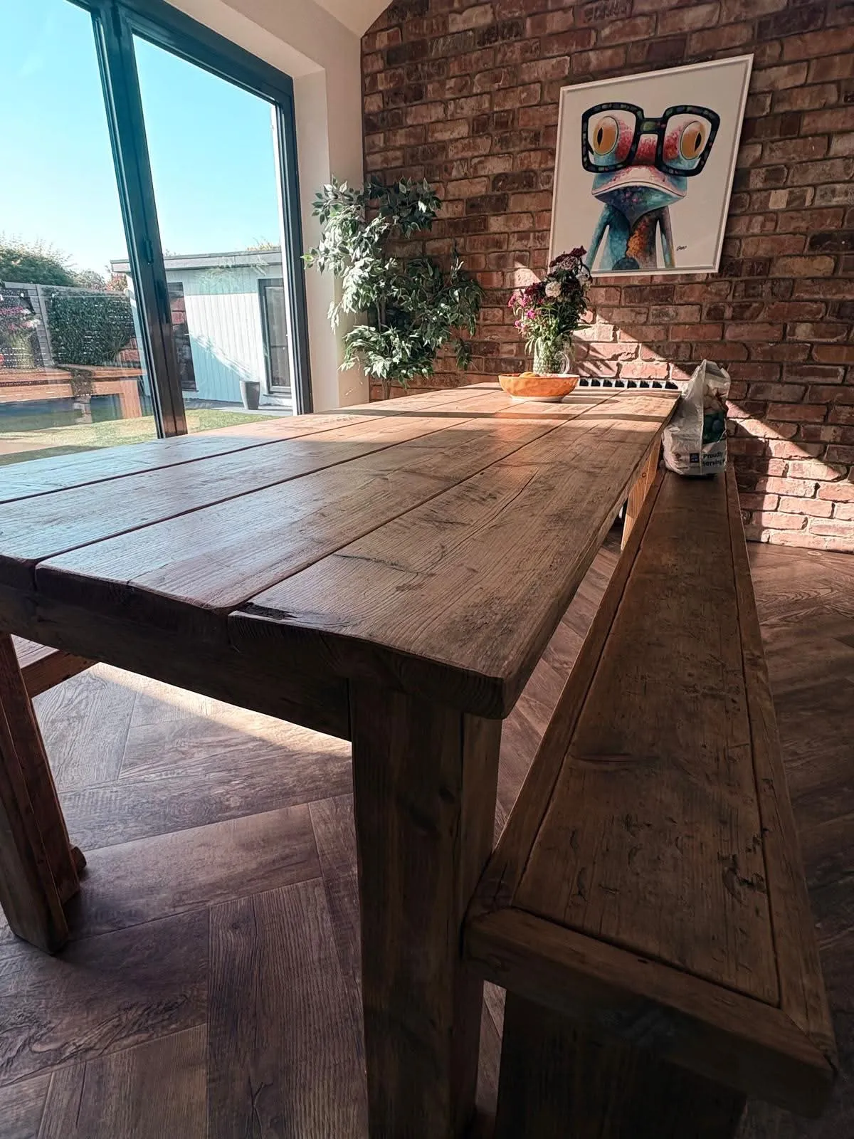 Rustic wooden dining table and bench in a holiday let, set for guests